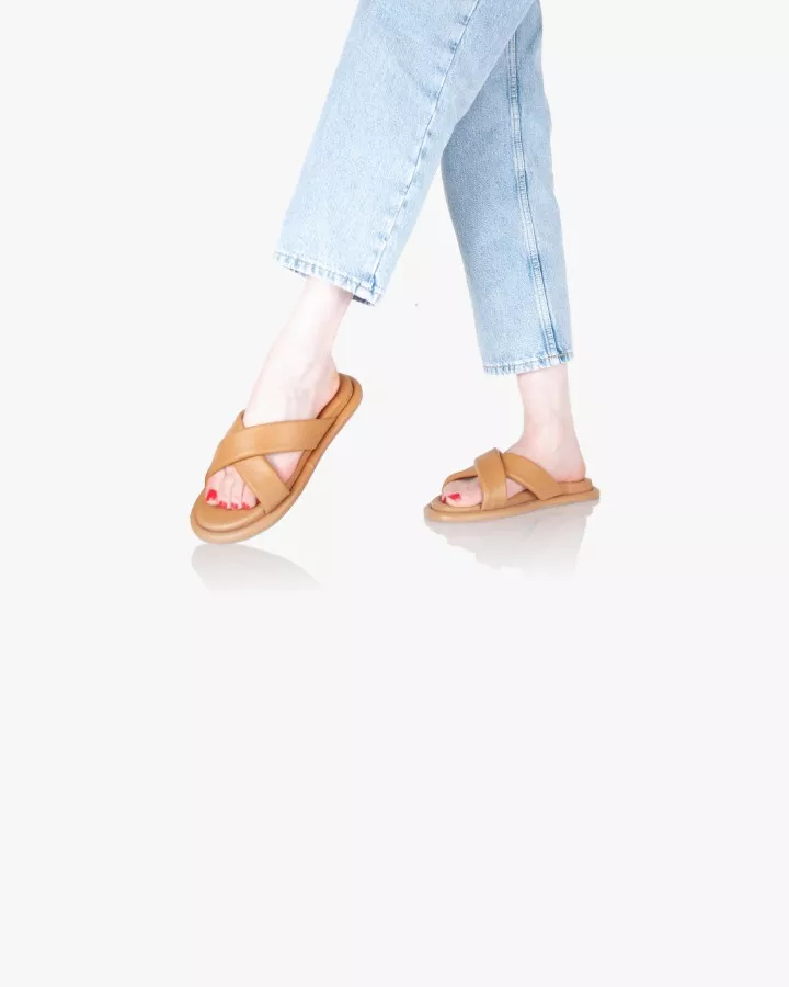 Sandales en cuir camel portées debout jambes croisées pied gauche levé