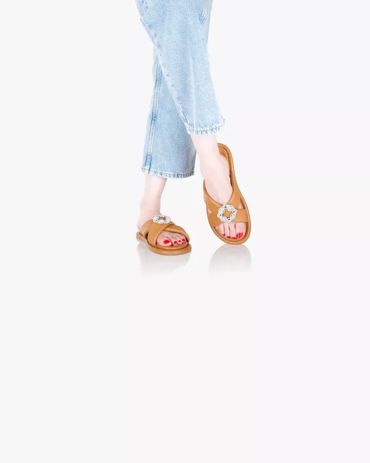 Sandales en cuir camel avec accessoires bijoux portées debout jambes croisées